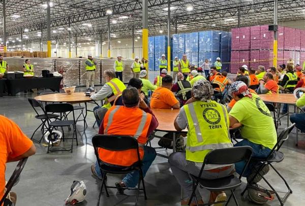 A 澳门足彩app construction crew gathers for a meeting in Bang Energy's giant warehouse